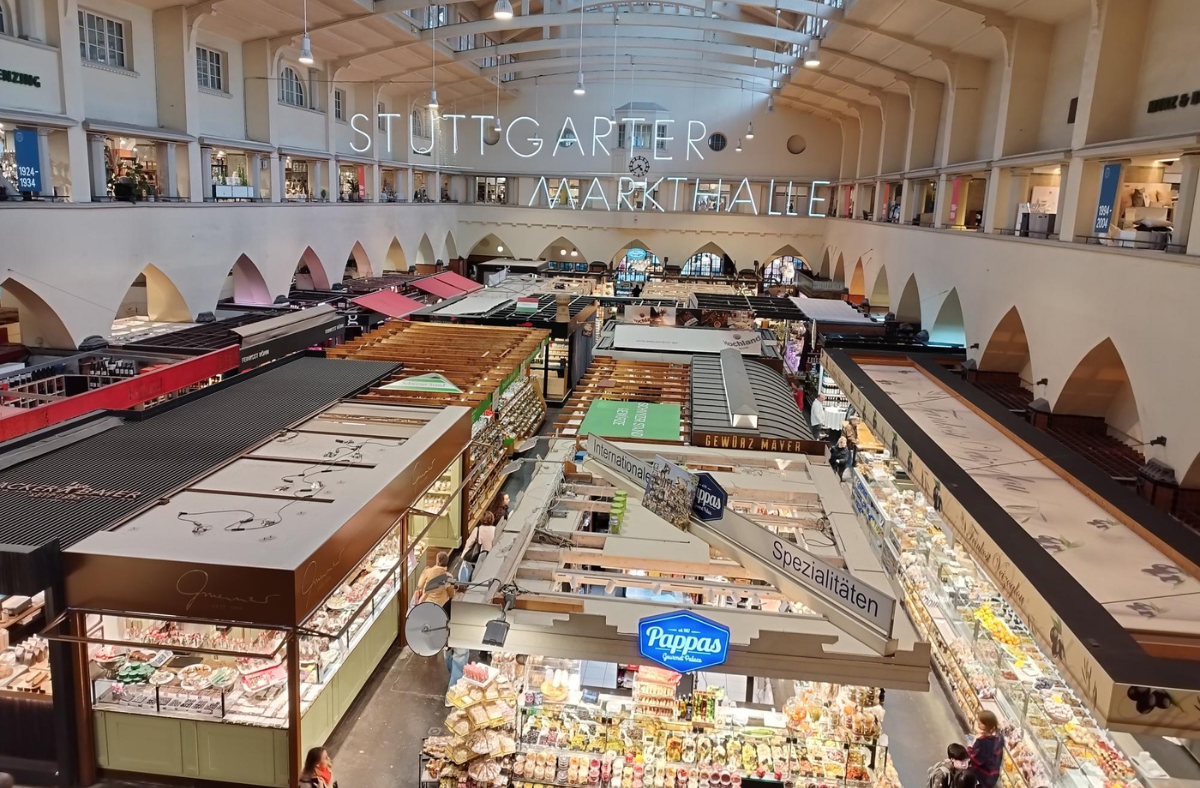 Ein Foto der Stuttgarter Markthalle von innen. Zu sehen sind die Stände von oben, sowie die Innenarchitektur des Gebäudes.